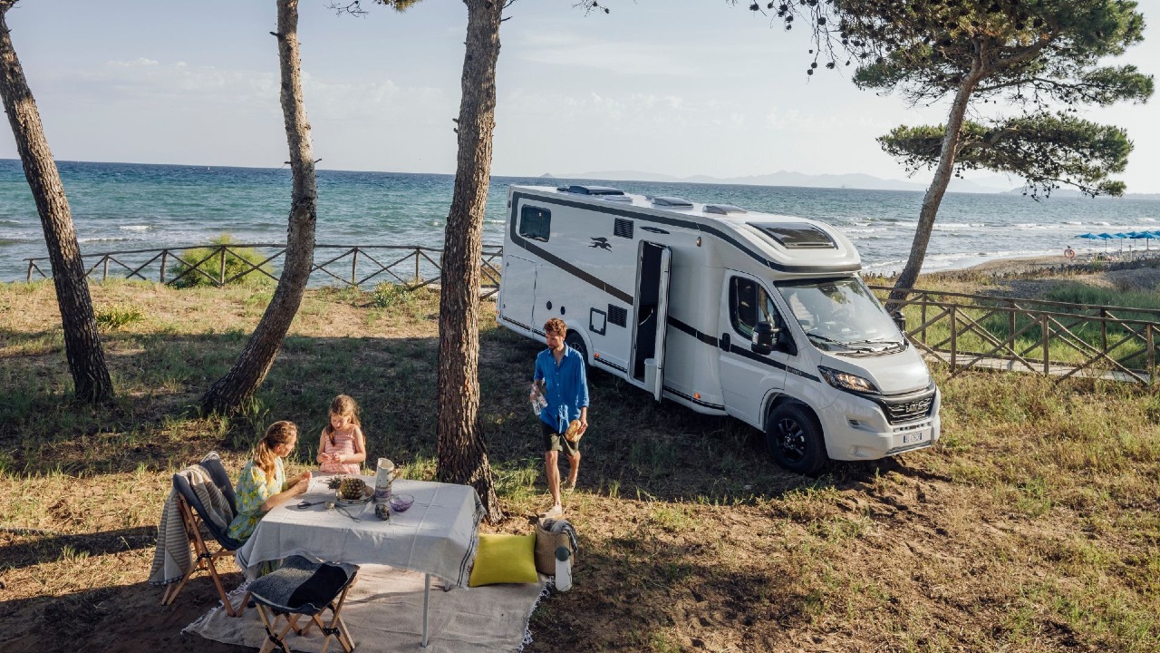 Une famille avec le camping-car au bord de l'eau
