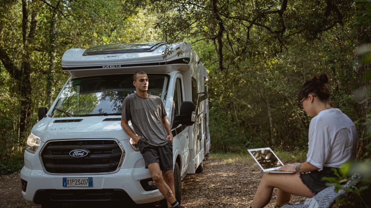 Deux personnes avec leur camping-car en forêt